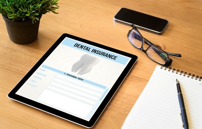 Dental insurance form on tablet on desk with notepad