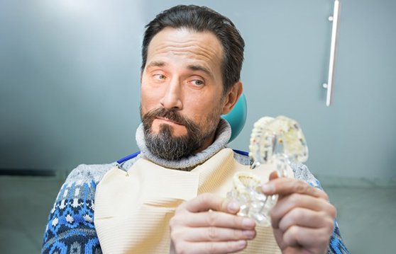 Man appraising a model of dentures