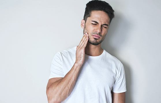 Man in white shirt experiencing tooth pain