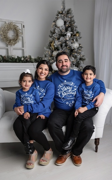 Doctor Navi Dhaliwal with her family in their living room with Christmas tree